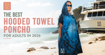 Adult wearing a hooded microfiber towel poncho on a beach after a swim