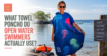 Open water swimmer changing under a hooded Max towel poncho by a lake